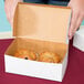 A white bakery box with two muffins inside.