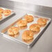 A Vollrath Wear-Ever bun pan filled with croissants on a stainless steel counter.