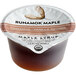 A single-serve cup of Runamok Cinnamon and Vanilla-Infused Maple Syrup with a label.