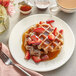 A plate of waffles with strawberries and Runamok Cinnamon and Vanilla-Infused Maple Syrup on a table.
