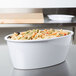 A white oval melamine casserole dish filled with pasta on a counter.