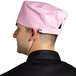 A man wearing a pink Uncommon Chef skull cap in a professional kitchen.