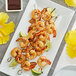 A plate of shrimp skewers with lime and Runamok Hibiscus Flower-Infused Maple Syrup.