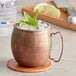 An Acopa Dark Antique Copper Moscow Mule Mug filled with ice and mint leaves.