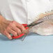 A person using Thunder Group nickel-plated steel fish shears to cut a fish.
