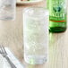 A glass of Mountain Valley Spring Water with ice and a green bottle on a table.