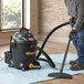 A man using a Shop-Vac wet/dry vacuum to clean a carpet.
