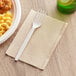 A white plastic fork on a OneUp by Choice Kraft dispenser napkin.