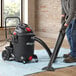 A man using a Shop-Vac wet / dry vacuum to clean a carpet.