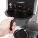 A hand using the buttons on a Bloomfield Koffee King automatic coffee brewer.