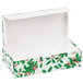 A white candy box with an open lid and holly leaves and berries on it.