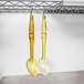 Two Cambro amber salad bar spoons hanging from a rack.