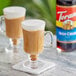 A glass mug of coffee with Torani Irish Cream Syrup and a bottle of Torani Irish Cream Syrup.