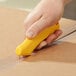 A person using a CrewSafe yellow safety utility knife to cut a box.