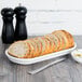 A white oval china bread tray holding sliced bread on a table.