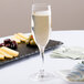 A Stolzle flute glass of champagne next to a plate of cheese and olives.