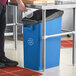 A man pouring something into a blue Lavex under-counter recycling bin.