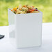 A white square container with pasta and vegetables.