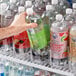 A hand using an Avantco 6 lane bottle organizer to hold a plastic bottle of soda.