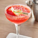 A customizable boat oar food pick in a strawberry margarita with lime and strawberries.