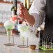 A bartender using a Flavour Blaster to add passion fruit aroma to a green cocktail.