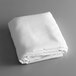A white folded Intedge cloth table cover on a gray surface.