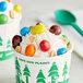 A cup of ice cream topped with M&M's Peanut Milk Chocolate candies and nuts.