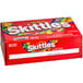 A red pouch of Skittles Original Fruity Candies with colorful candies.