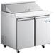 An Avantco stainless steel refrigerated sandwich prep table with two doors and a deep cutting board.