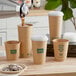 A person pouring coffee into a brown paper cup with a New Roots translucent compostable paper hot cup lid.
