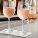 Two Acopa Select Flora wine glasses filled with pink wine on a table.