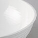 A close-up of a Cambro white round ribbed bowl on a white surface.