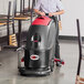 A person using a Viper cordless walk behind floor scrubber to clean a floor.