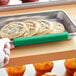 A hand using a green silicone clip to identify a tray of cookies.