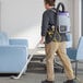A man using a ProTeam backpack vacuum in a corporate cafeteria.