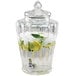 A Stylesetter glass beverage dispenser with water and lemons on a counter.