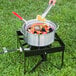 A person boiling seafood in a Backyard Pro aluminum pot on a propane stove outdoors.