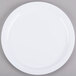 A Carlisle white melamine plate with a white rim on a gray surface.