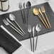 Acopa Odin flatware set with a spoon and fork on a black surface.