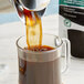 A person pouring Lavazza Grand Selezione ground coffee into a glass mug.