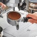 A hand pouring Lavazza Espresso Italiano from an espresso machine.