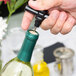 A hand using a Franmara black plastic pocket corkscrew to open a bottle of wine.