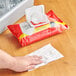 A hand using Sani Professional wet wipes to clean a kitchen counter.