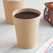 Two Choice 12 oz. Kraft Poly paper hot cups filled with coffee on a table in a coffee shop.