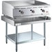 A stainless steel Cooking Performance Group gas griddle with knobs on a stainless steel Regency Equipment stand.