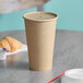 A Kraft paper hot cup on a table with a cup of coffee.