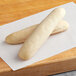 Two long white Turano gourmet bread sticks on a wooden surface.