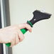 A hand holding a Unger ErgoTec scraper with a green handle.