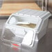 A white Rubbermaid shelf ingredient storage bin with a sliding lid and scoop inside.