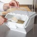 A person using a white Rubbermaid ingredient storage bin to scoop rice into a white bowl.